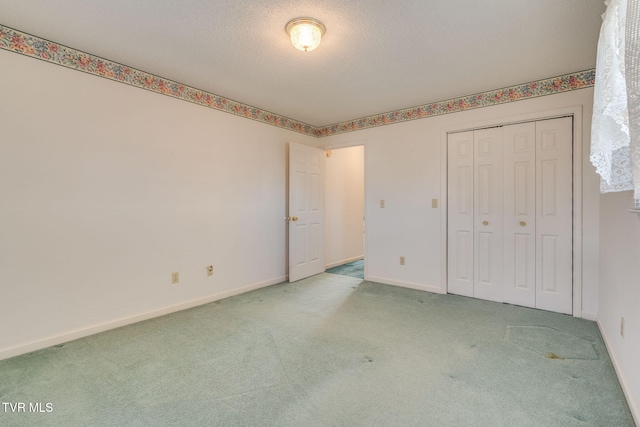 unfurnished bedroom featuring a closet, light carpet, a textured ceiling, and baseboards