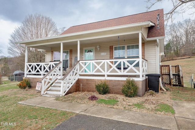 bungalow-style home featuring covered porch, roof with shingles, and stairway