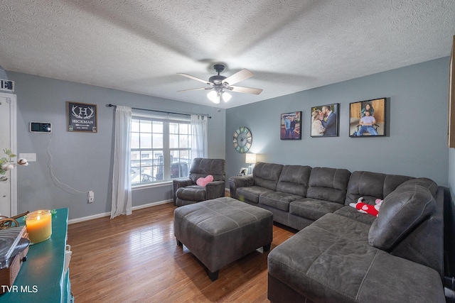 living room featuring ceiling fan, a textured ceiling, baseboards, and wood finished floors