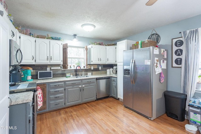 kitchen featuring appliances with stainless steel finishes, white cabinets, light countertops, and a sink