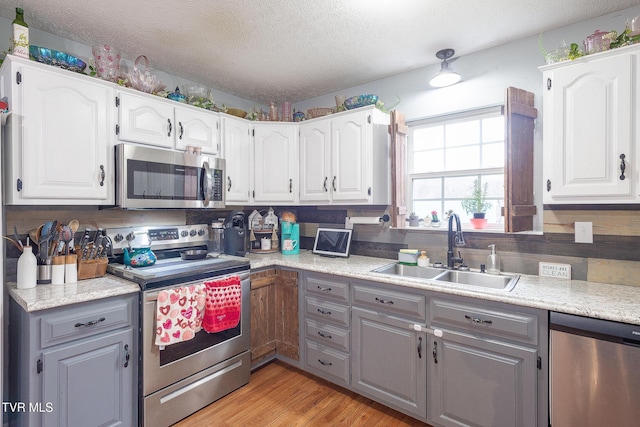 kitchen with white cabinetry, stainless steel appliances, a sink, and light countertops