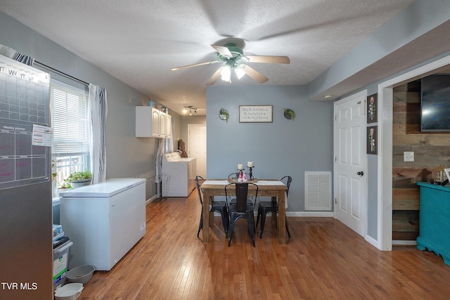 dining area with visible vents, light wood-style flooring, a ceiling fan, a textured ceiling, and washer / dryer