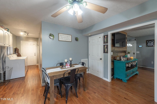 dining space with a textured ceiling, washing machine and dryer, visible vents, baseboards, and light wood finished floors