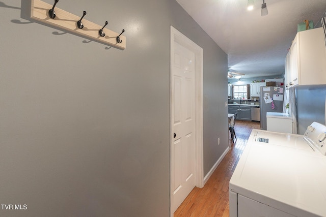 laundry area with cabinet space, light wood finished floors, a sink, and washing machine and clothes dryer