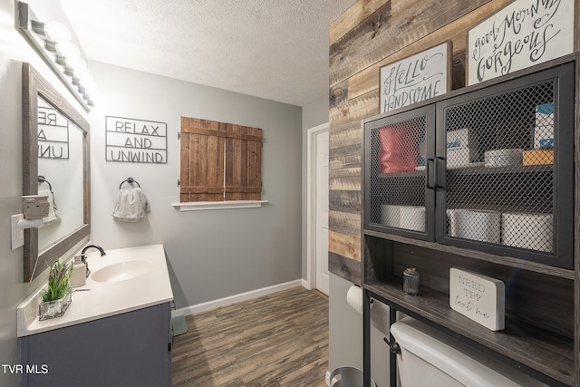 bathroom with baseboards, toilet, wood finished floors, a textured ceiling, and vanity