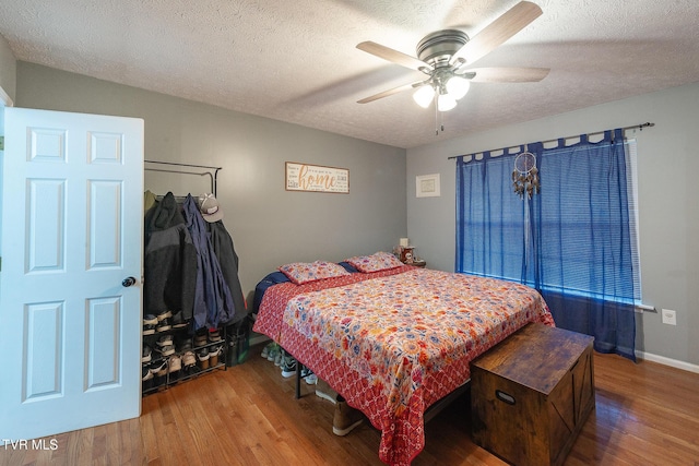 bedroom with a textured ceiling, ceiling fan, wood finished floors, and baseboards