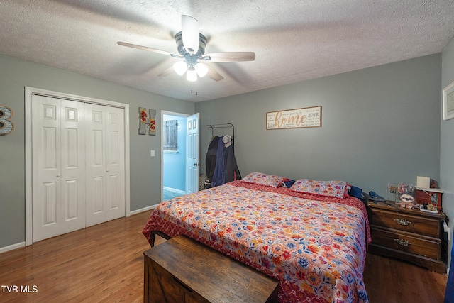 bedroom with a textured ceiling, a closet, wood finished floors, and baseboards