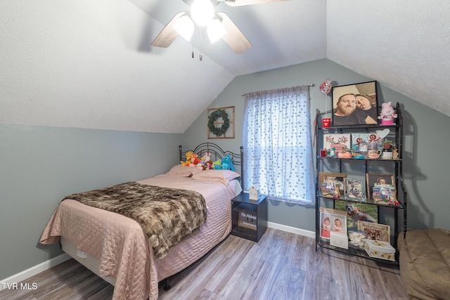 bedroom with a textured ceiling, multiple windows, and wood finished floors