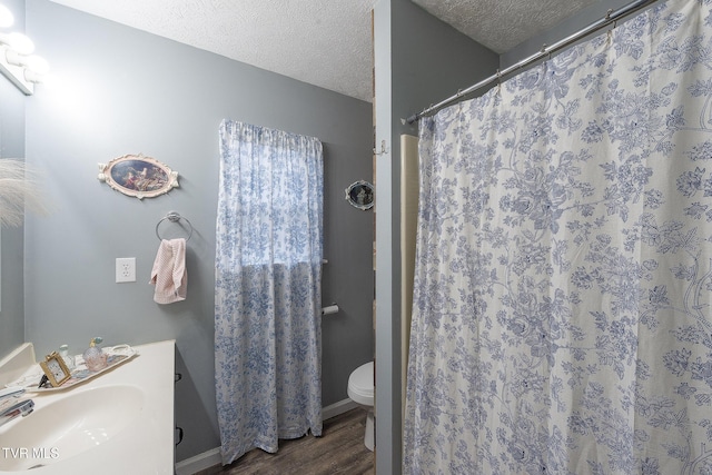 bathroom with toilet, a sink, a textured ceiling, wood finished floors, and a shower with curtain