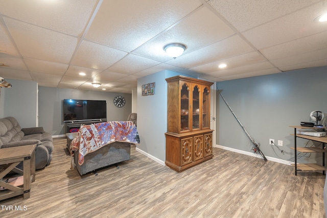 living area featuring a paneled ceiling, baseboards, wood finished floors, and recessed lighting