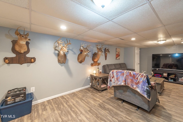 living room with a paneled ceiling, baseboards, and wood finished floors