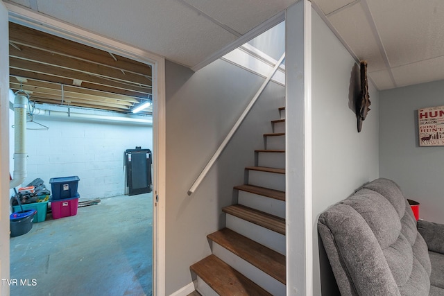 stairway with unfinished concrete flooring and concrete block wall