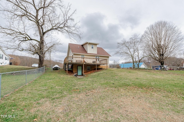 back of house featuring fence, a lawn, and a wooden deck