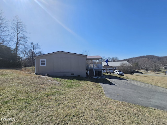 view of side of home featuring crawl space, stairs, aphalt driveway, and a yard