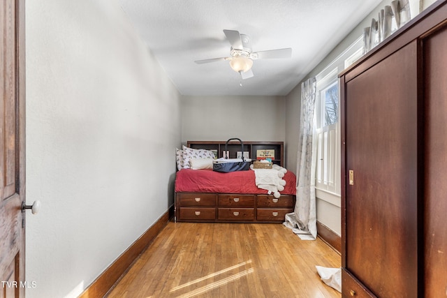 bedroom with light wood finished floors, baseboards, and a ceiling fan