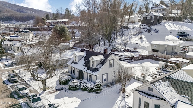 snowy aerial view featuring a residential view and a mountain view