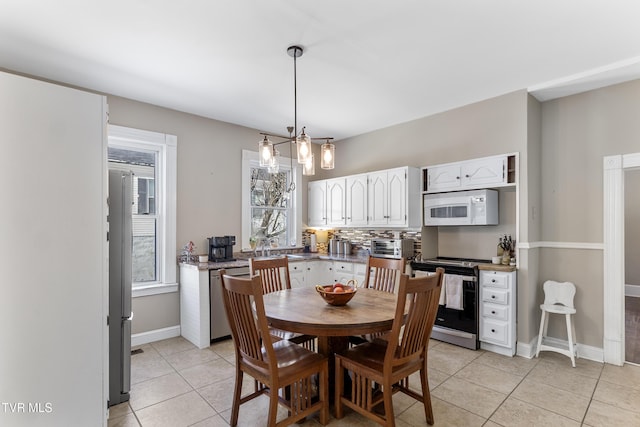 dining area with a chandelier, baseboards, and light tile patterned floors