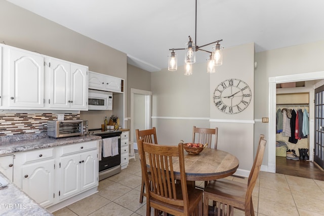 dining room featuring light tile patterned floors, an inviting chandelier, baseboards, and a toaster