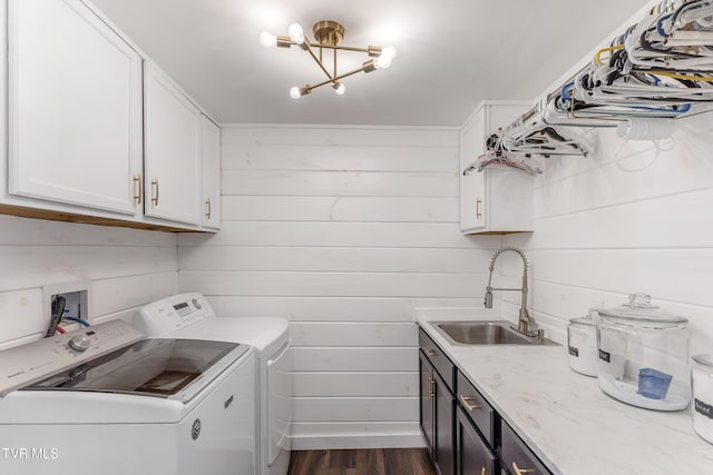 washroom featuring cabinet space, dark wood finished floors, washer and dryer, wood walls, and a sink