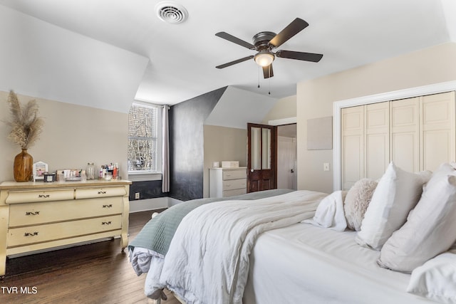 bedroom with lofted ceiling, visible vents, dark wood-type flooring, ceiling fan, and baseboards