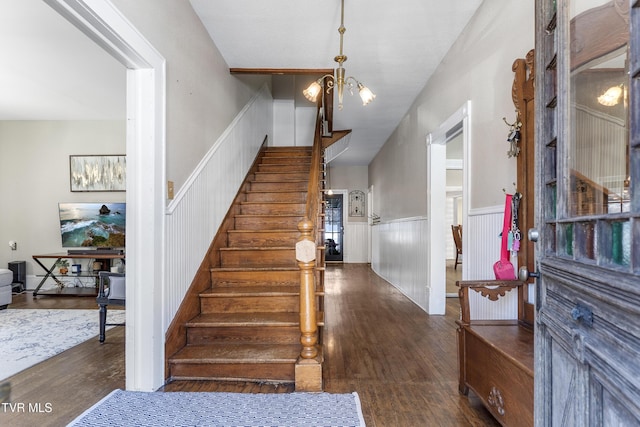 staircase featuring a chandelier, wainscoting, and wood finished floors