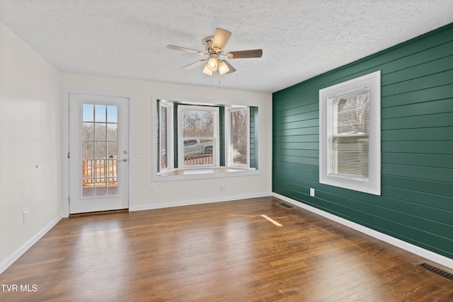 unfurnished room with a textured ceiling, visible vents, and wood finished floors