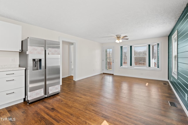 kitchen with a textured ceiling, dark wood-type flooring, visible vents, white cabinets, and stainless steel refrigerator with ice dispenser