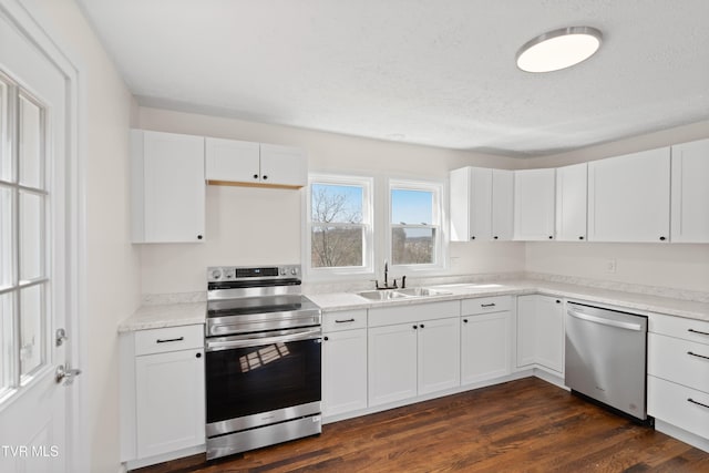 kitchen with stainless steel appliances, light countertops, dark wood-type flooring, white cabinets, and a sink