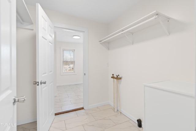 laundry area featuring marble finish floor, laundry area, and baseboards