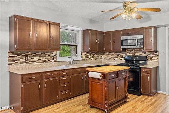 1016 Grace Dr, Johnson City, TN 37604 - kitchen with black range with gas cooktop, stainless steel microwave, a sink, ceiling fan, and light wood finished floors