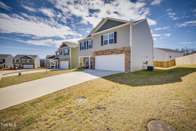 view of front of property with an attached garage, fence, concrete driveway, stone siding, and a front yard