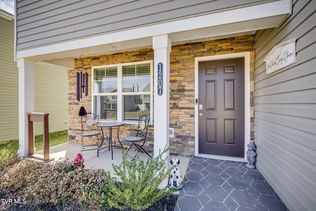 property entrance with stone siding and a porch