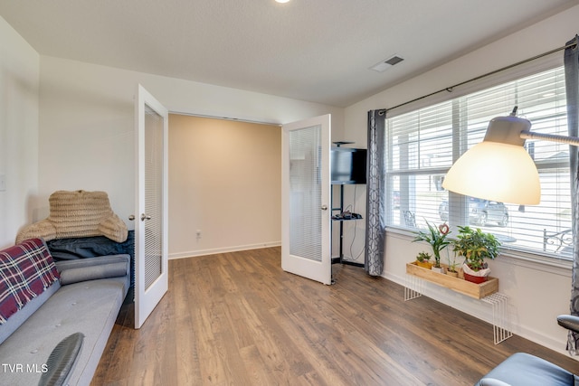 living area with baseboards, visible vents, vaulted ceiling, and wood finished floors