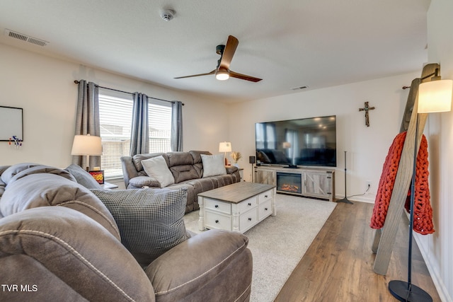 living room with baseboards, light wood-style flooring, visible vents, and a ceiling fan