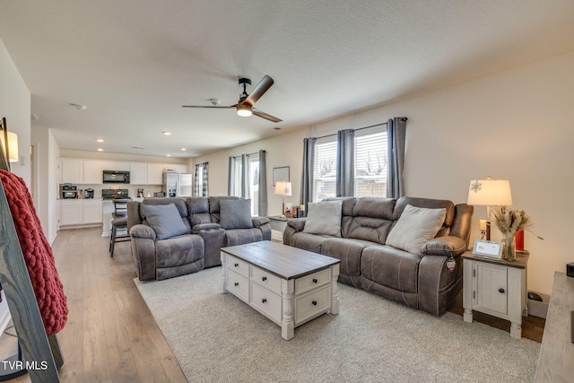 living room with recessed lighting, ceiling fan, a textured ceiling, and light wood finished floors