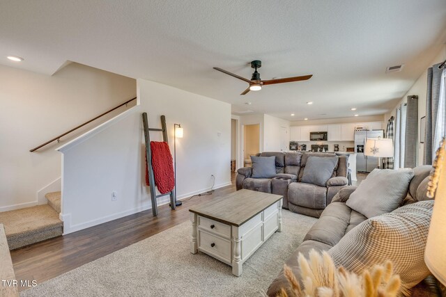 living area with recessed lighting, visible vents, stairway, wood finished floors, and baseboards