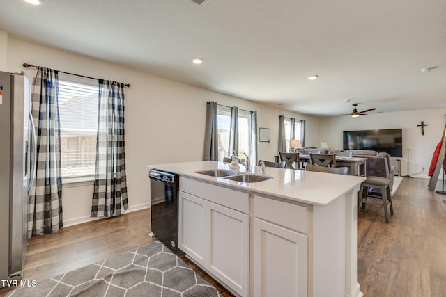 kitchen with dishwasher, wood finished floors, a sink, and freestanding refrigerator