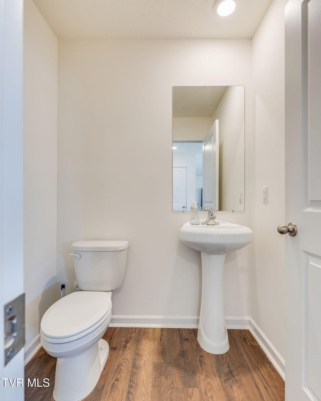 bathroom featuring baseboards, toilet, and wood finished floors