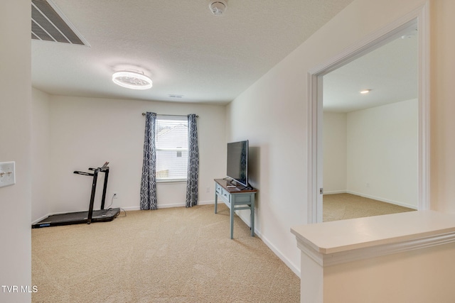 workout area with baseboards, a textured ceiling, visible vents, and carpet flooring