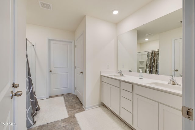 bathroom with visible vents, a sink, baseboards, and double vanity