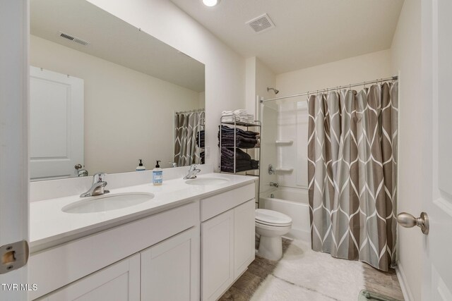 full bath with visible vents, a sink, toilet, and double vanity