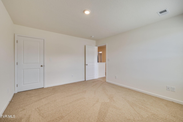 spare room featuring carpet flooring, visible vents, and baseboards