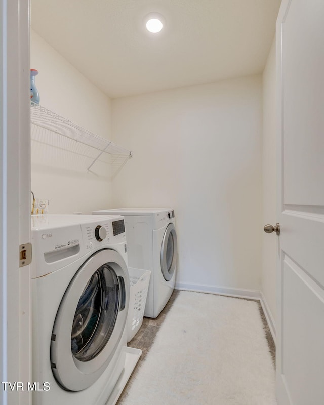 washroom featuring laundry area, separate washer and dryer, and baseboards