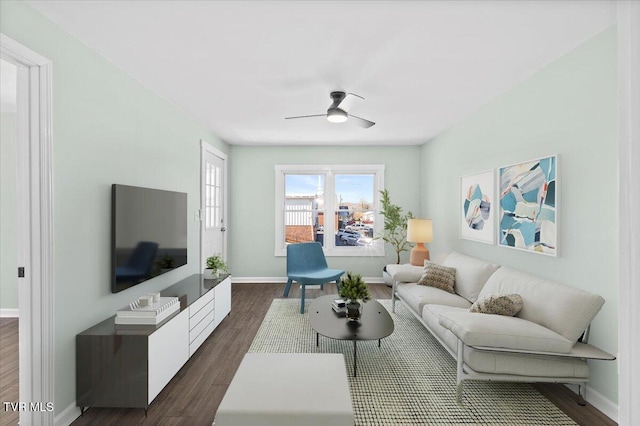 living room featuring ceiling fan, dark wood-type flooring, and baseboards