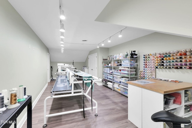 interior space with track lighting, vaulted ceiling, baseboards, and wood finished floors