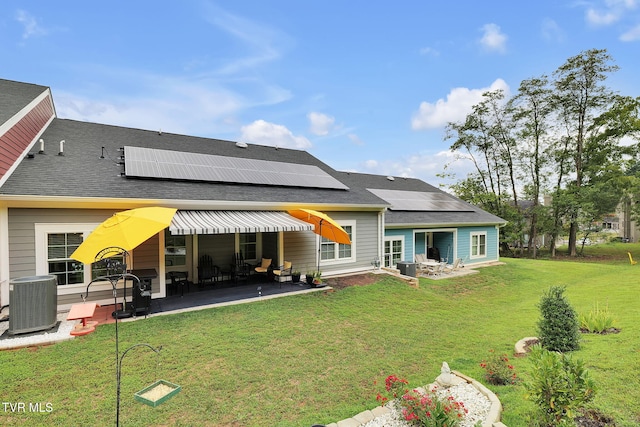 rear view of house featuring central AC, a patio, a lawn, and roof mounted solar panels