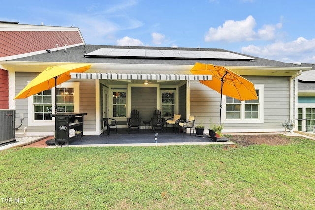 rear view of house with a patio area, roof with shingles, central AC, and a yard