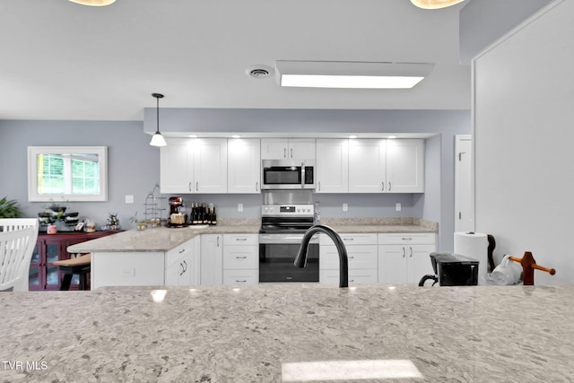 kitchen with appliances with stainless steel finishes, visible vents, white cabinets, and decorative light fixtures