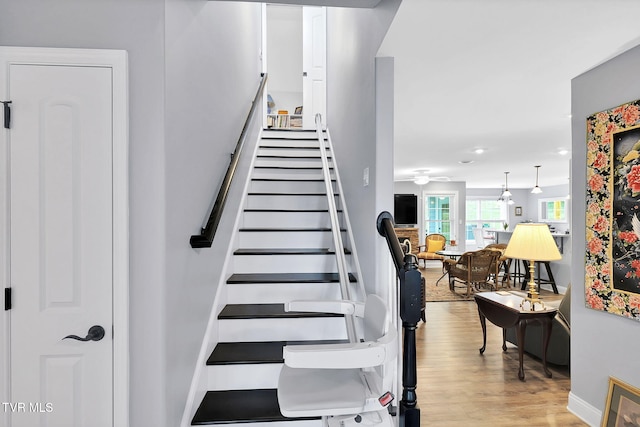 staircase featuring wood finished floors and baseboards