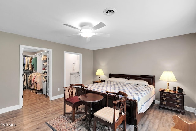 bedroom with visible vents, a spacious closet, baseboards, and wood finished floors